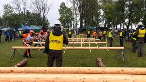 Na zdjęciu widzimy sędziego zawodów drwali, który stoi przodem do kamery i przygotowuje się do rozpoczęcia konkurencji okrzesywania.
