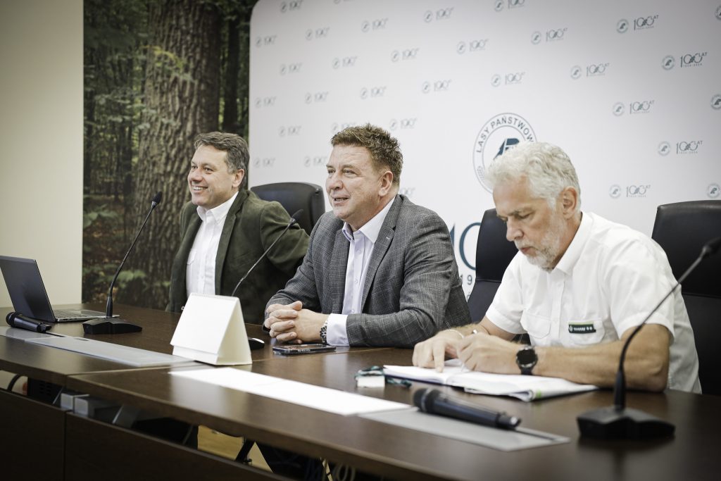 Na zdjęciu widać trzech dyrektorów siedzących w sali konferencyjnej przed rozpoczęciem spotkania.